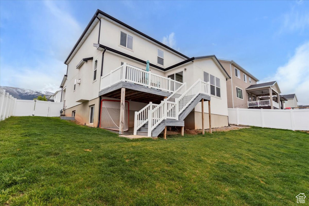 Rear view of house with stairs, a wooden deck, and stucco siding