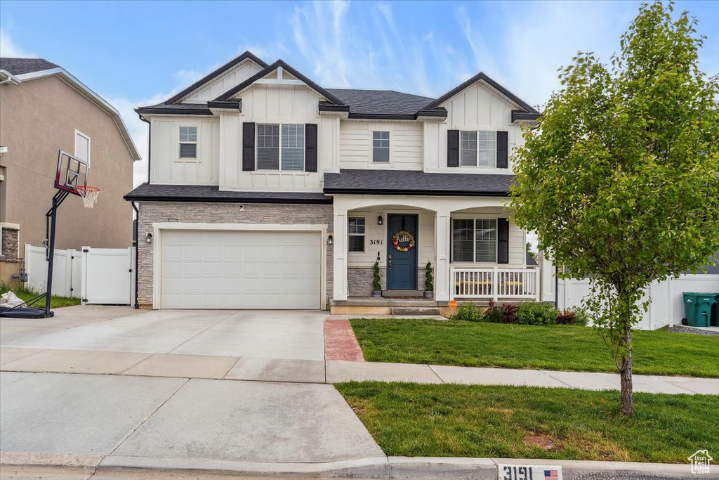 View of front of home featuring board and batten siding, a porch, driveway, a garage, and a gate