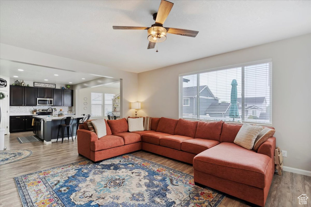 Living area featuring ceiling fan, light wood finished floors, and baseboards