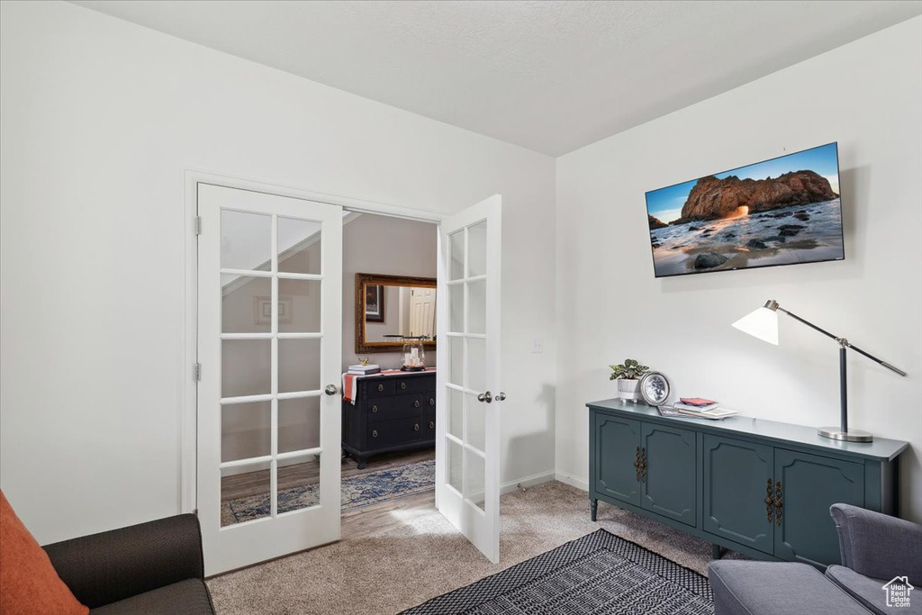 Living area with french doors, light carpet, and baseboards