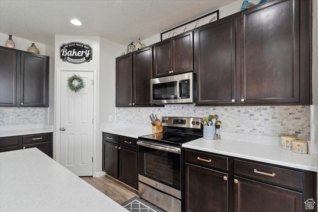 Kitchen with appliances with stainless steel finishes, light countertops, light wood-style flooring, and decorative backsplash