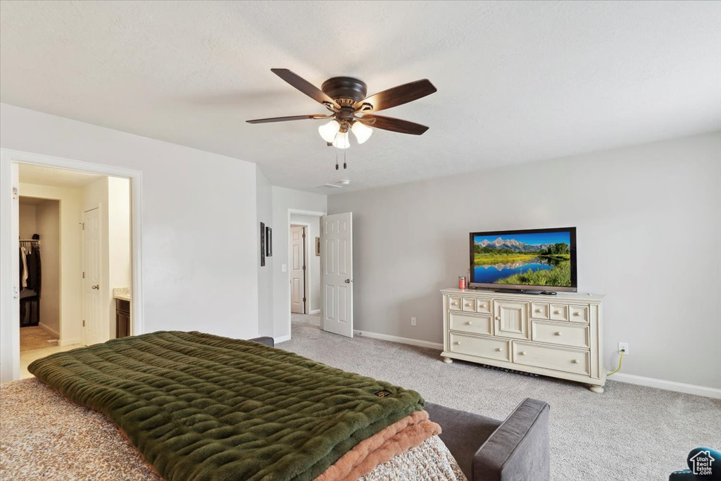 Bedroom with baseboards, light carpet, ceiling fan, and connected bathroom