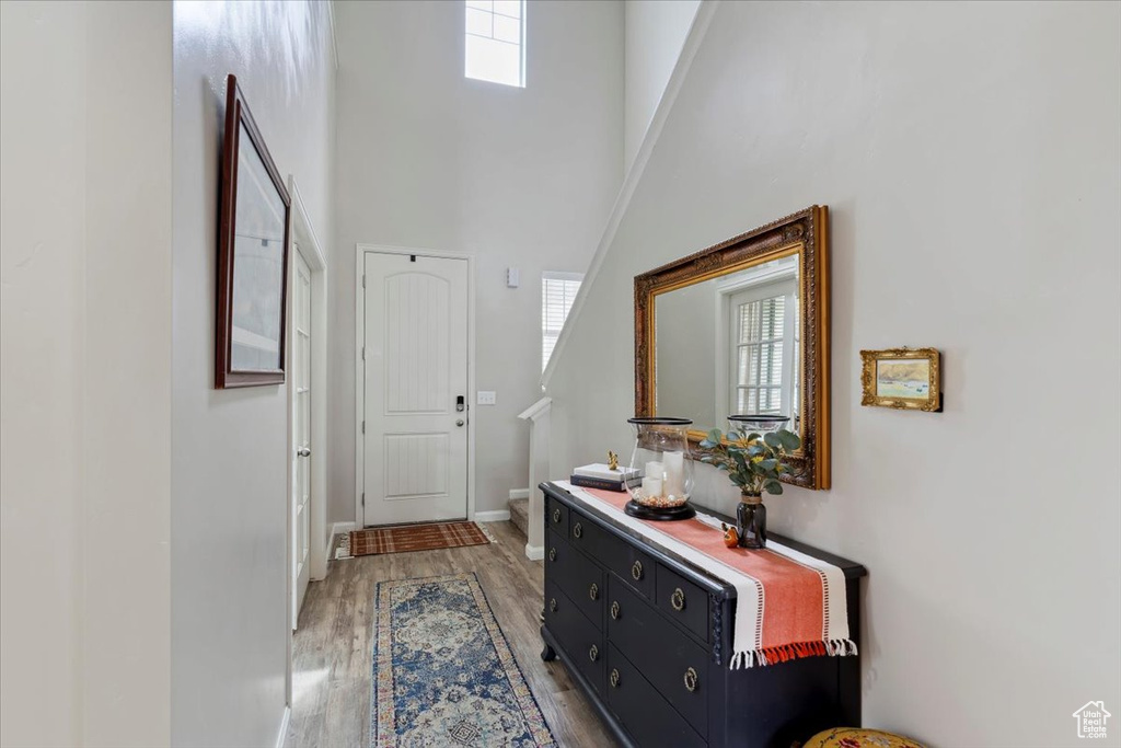 Foyer entrance featuring a towering ceiling, light wood finished floors, baseboards, and stairs
