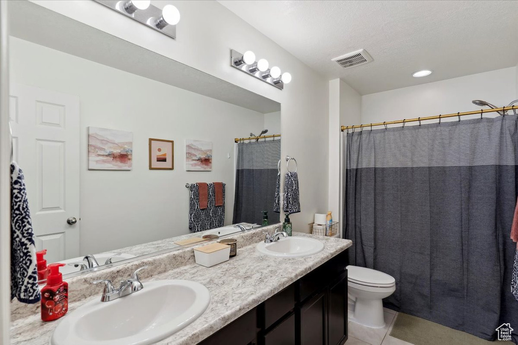 Full bath with toilet, double vanity, tile patterned floors, and a shower with curtain