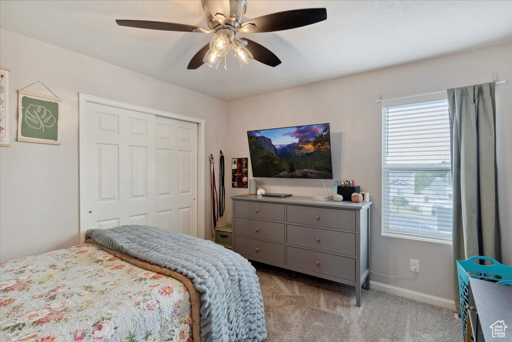 Carpeted bedroom featuring multiple windows, a closet, baseboards, and ceiling fan