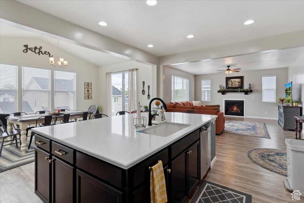 Kitchen with a sink, a glass covered fireplace, light wood finished floors, light countertops, and vaulted ceiling