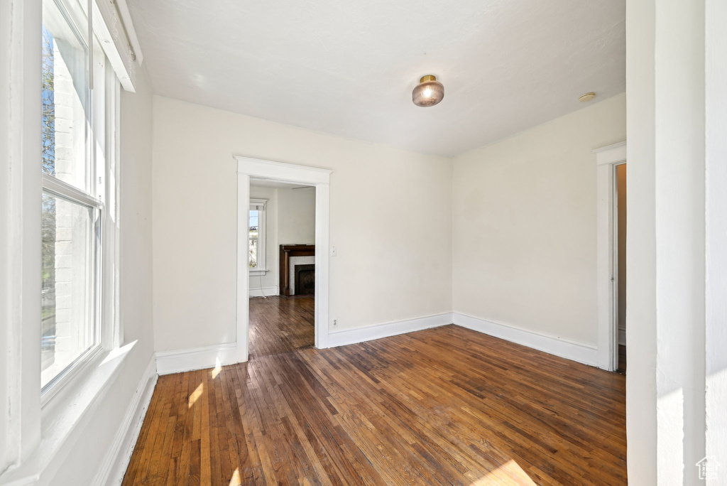 Empty room featuring wood-type flooring, a fireplace, and baseboards