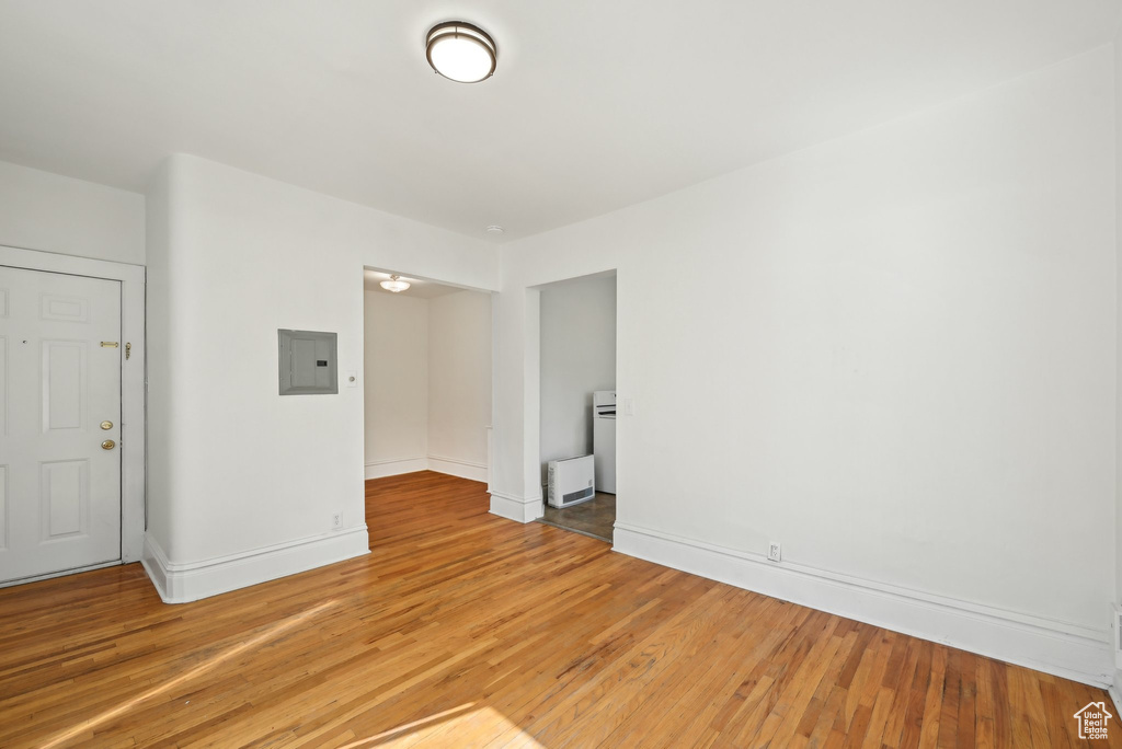 Unfurnished room with electric panel, light wood-style floors, and baseboards