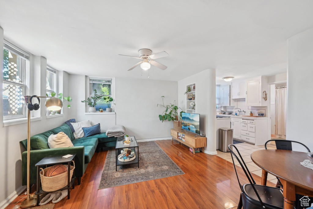 Living room featuring a ceiling fan, light wood finished floors, and baseboards