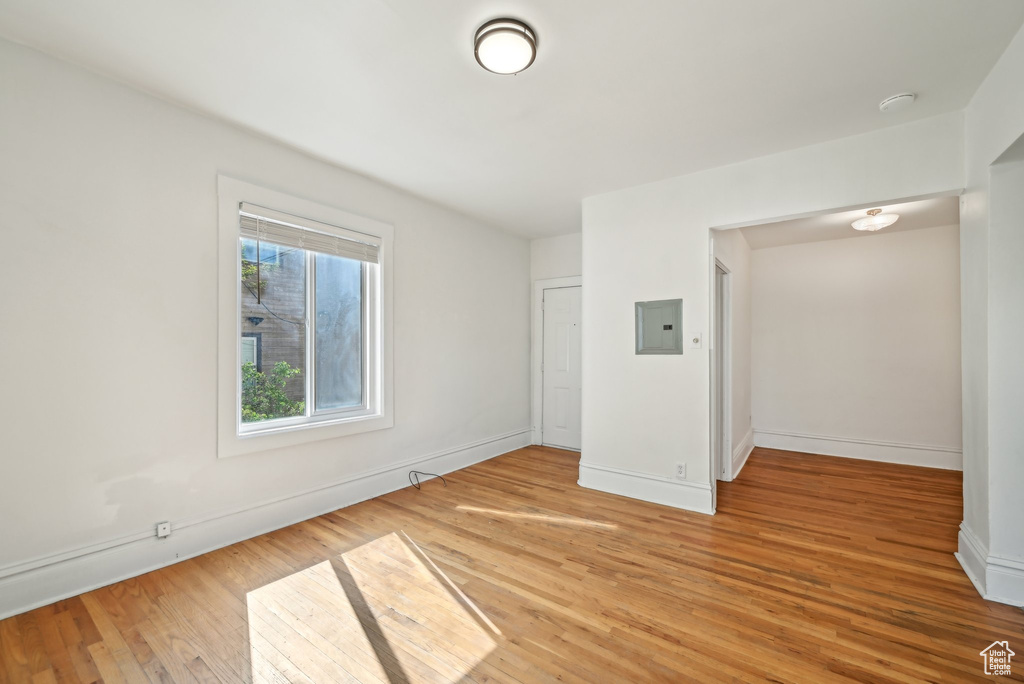 Spare room with light wood-type flooring, baseboards, electric panel, and a smoke detector