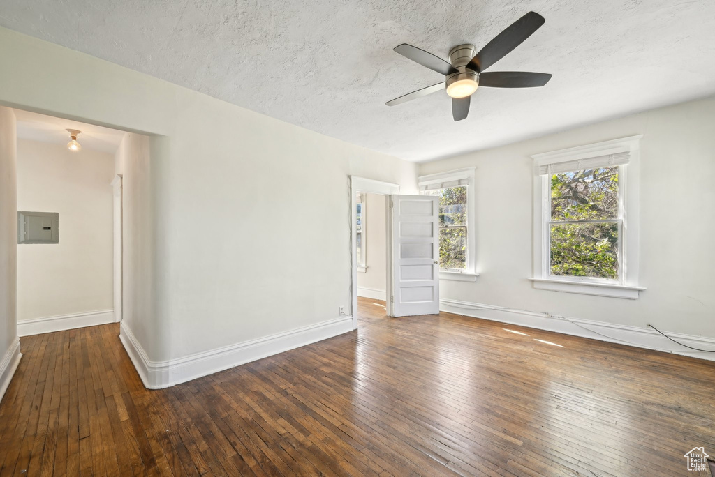 Unfurnished room featuring ceiling fan, hardwood / wood-style floors, baseboards, a textured ceiling, and electric panel