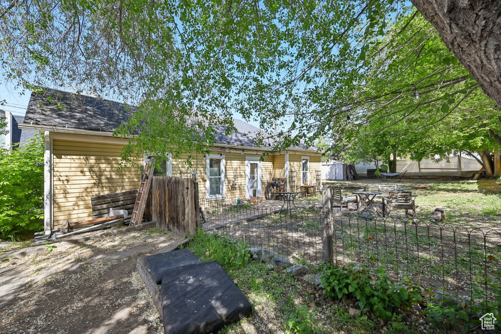 View of front of home with fence, a storage shed, and an outdoor structure