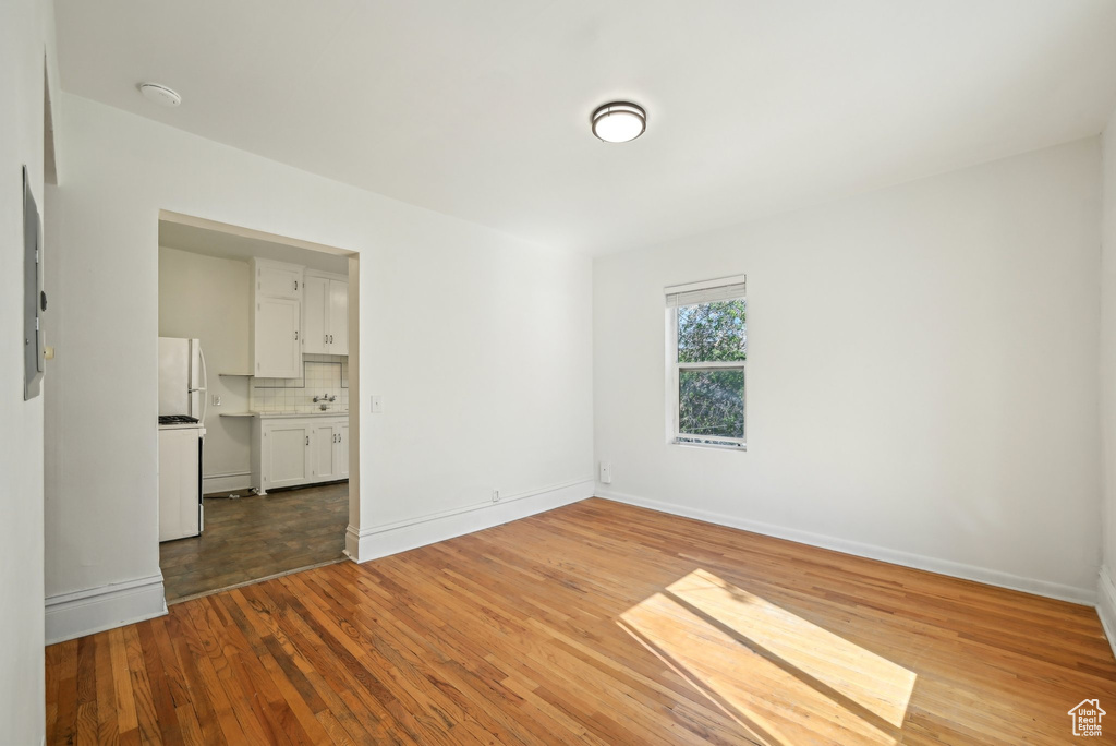 Spare room with wood finished floors, baseboards, and a smoke detector