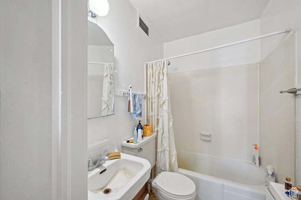 Full bath featuring a sink, toilet, and shower / bathtub combination with curtain