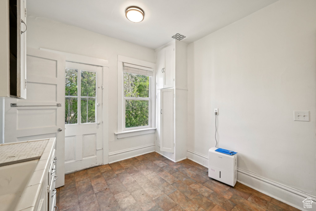 Doorway to outside with stone finish flooring and baseboards