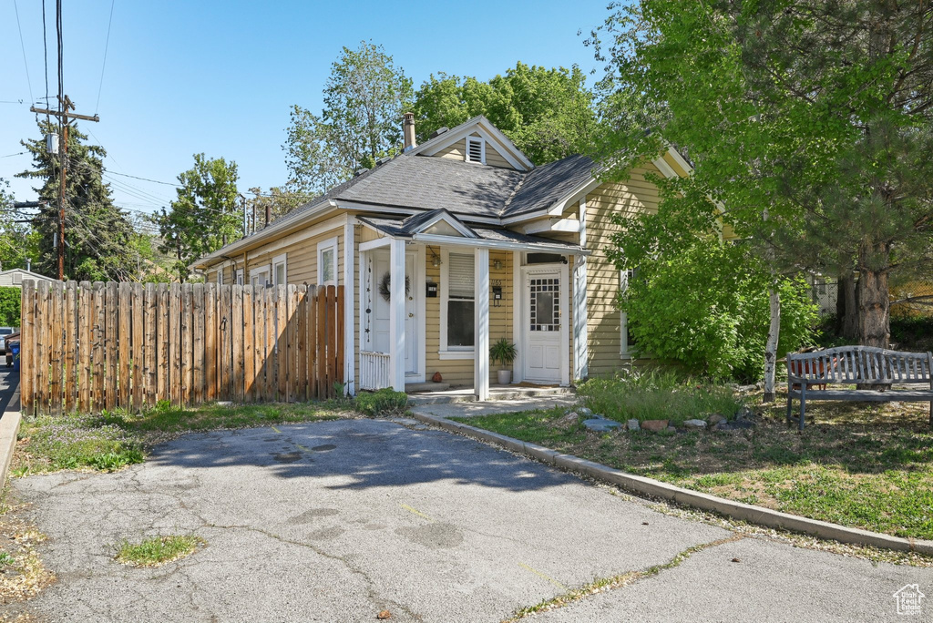 View of front of property featuring fence and a shingled roof