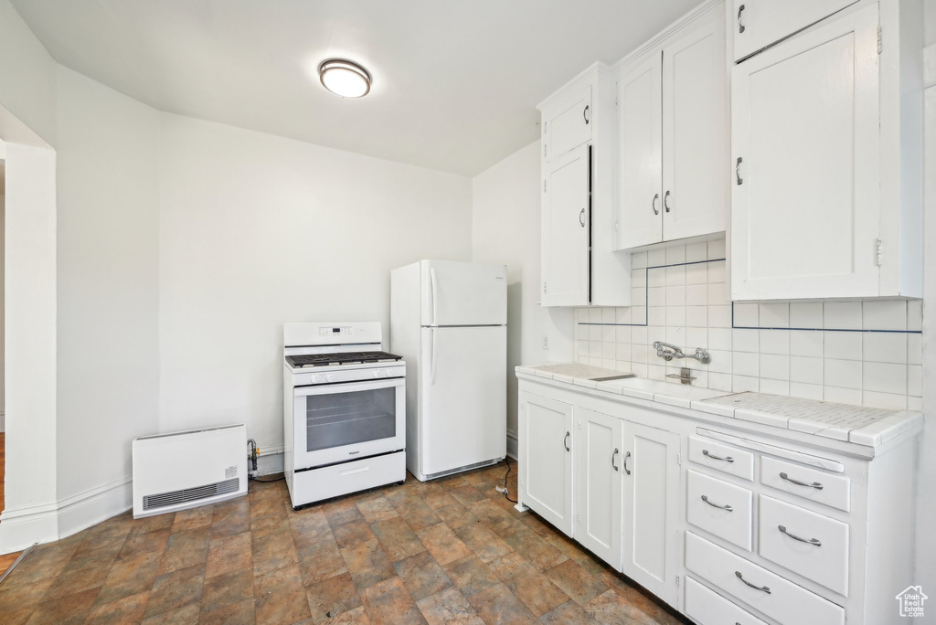 Kitchen featuring white appliances, a sink, tile counters, tasteful backsplash, and white cabinets
