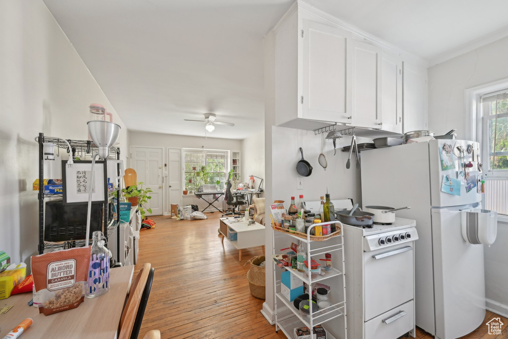 Kitchen with plenty of natural light, white appliances, ceiling fan, and white cabinets