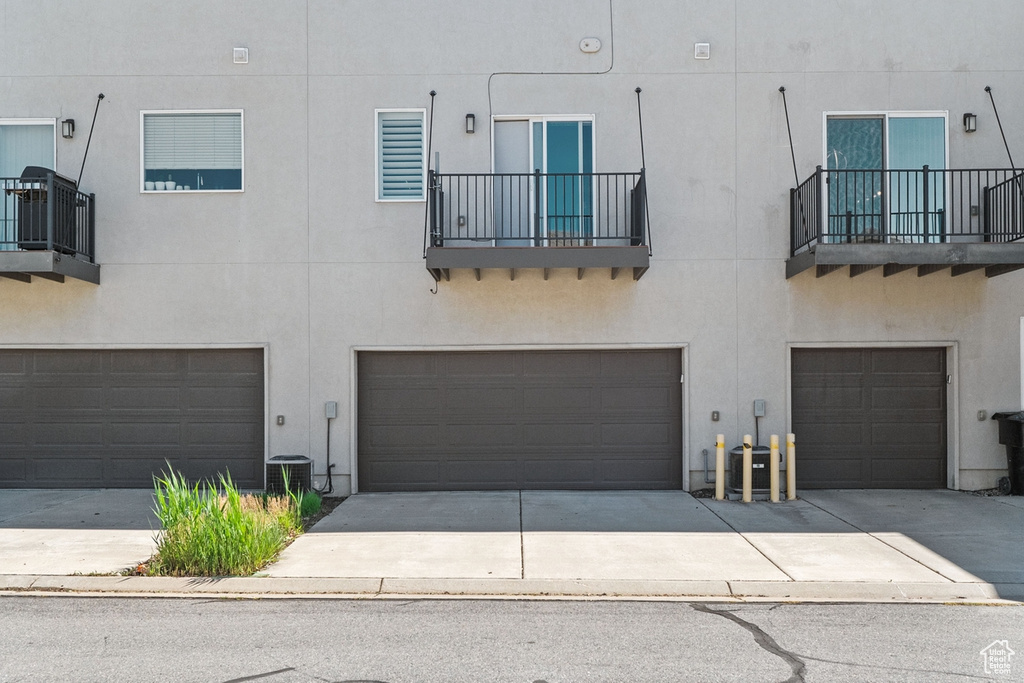 View of front of house featuring an attached garage, stucco siding, driveway, and a balcony