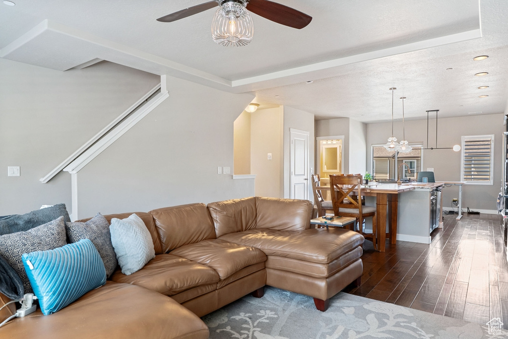 Living room featuring dark wood-style flooring, ceiling fan, baseboards, and recessed lighting