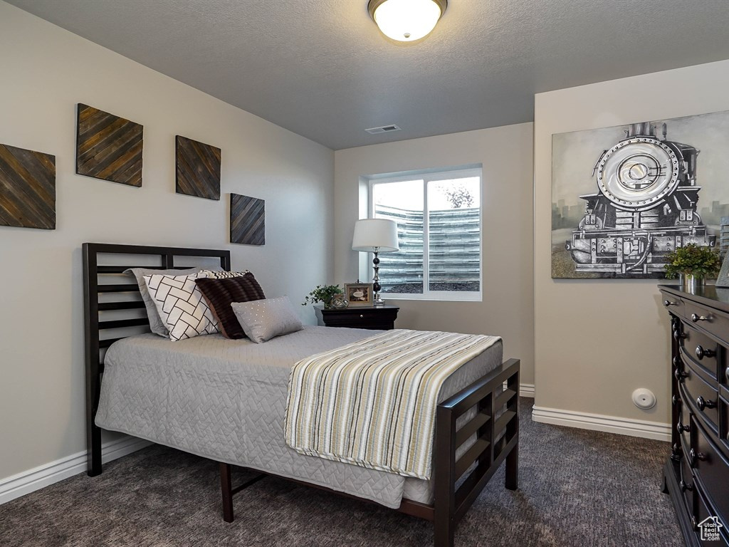 Bedroom with dark carpet and baseboards