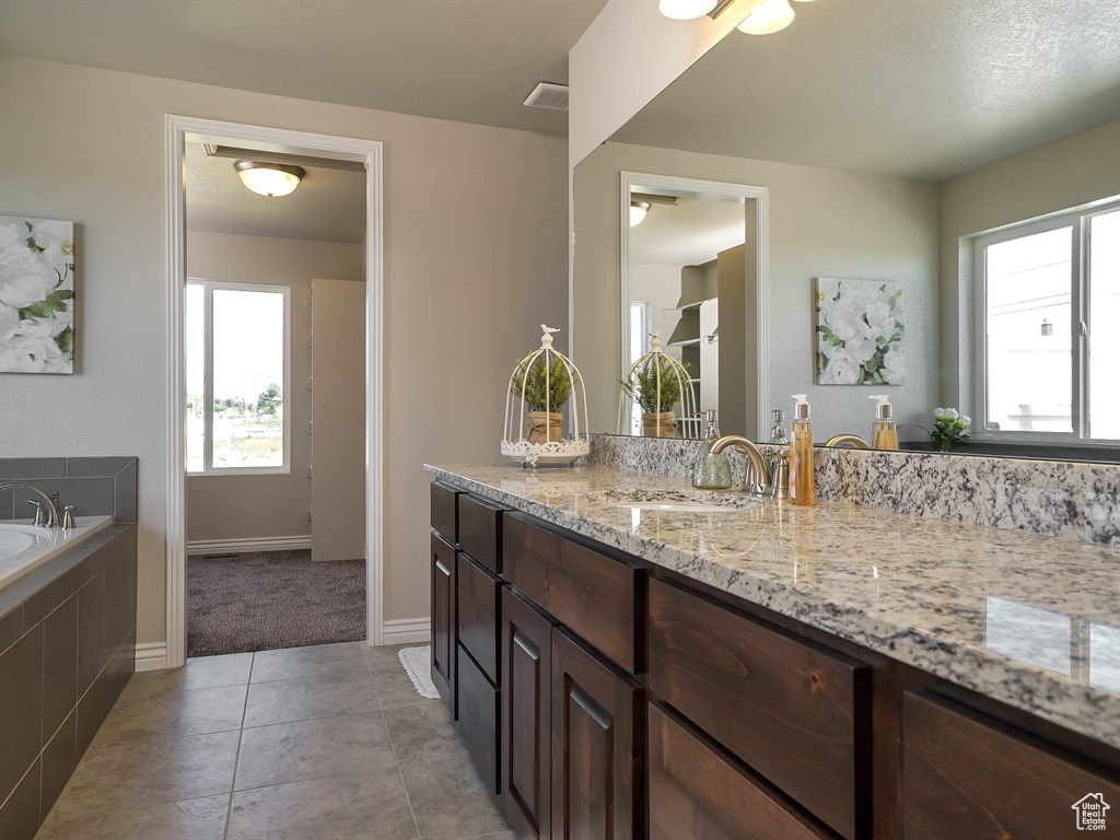 Bathroom with vanity, a garden tub, baseboards, and tile patterned floors