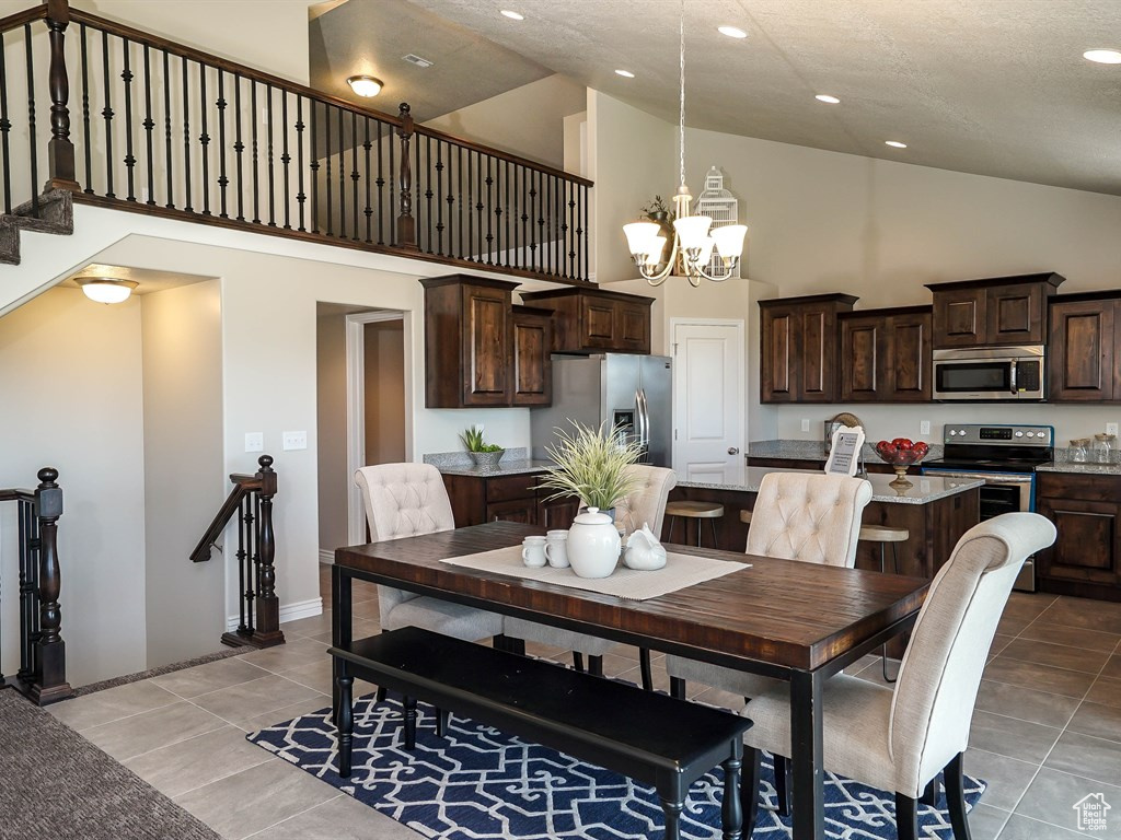 Dining area with high vaulted ceiling, a chandelier, light tile patterned flooring, recessed lighting, and baseboards