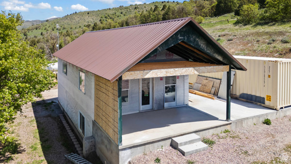 View of front of property featuring a patio, a mountain view, metal roof, and a forest view