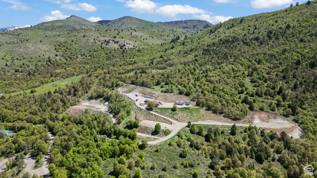 Aerial view of property and surrounding area featuring a forest and a mountain backdrop