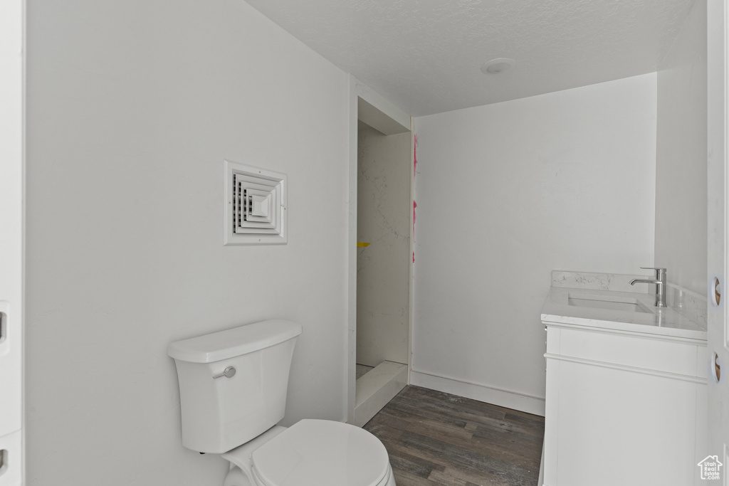 Bathroom with toilet, wood finished floors, vanity, and walk in shower