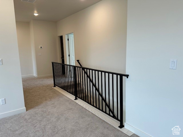 Hallway featuring an upstairs landing and carpet