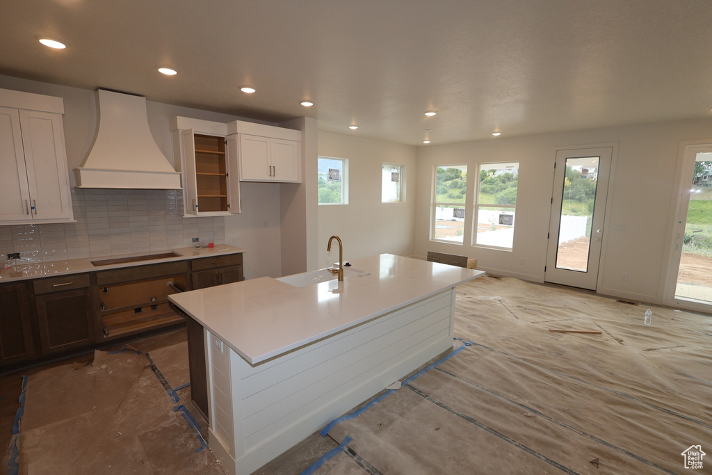 Kitchen with custom exhaust hood, black electric cooktop, decorative backsplash, recessed lighting, and light countertops