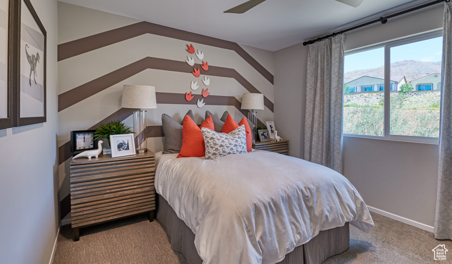 Carpeted bedroom featuring baseboards, ceiling fan, and a mountain view
