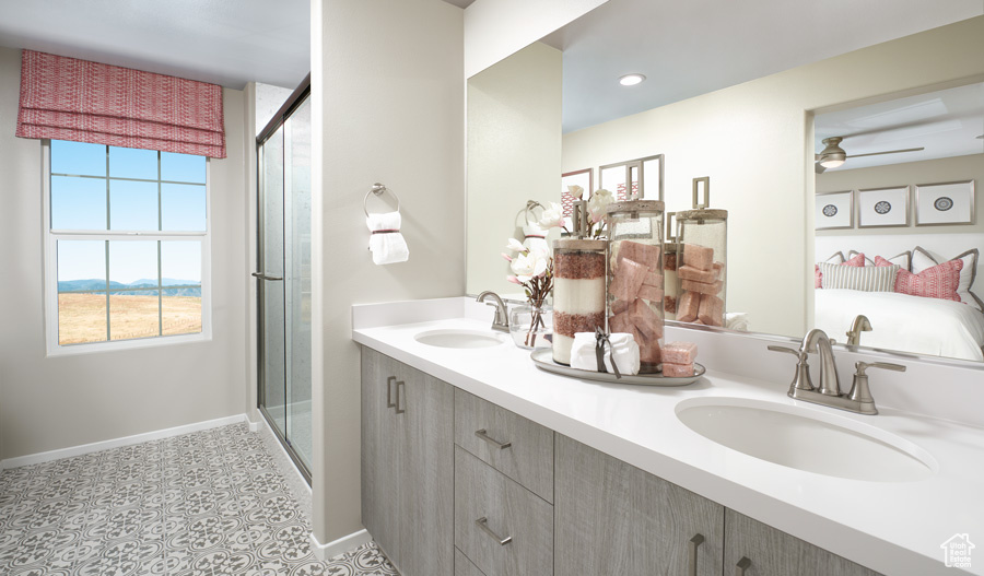 Full bath with baseboards, a stall shower, double vanity, and ceiling fan