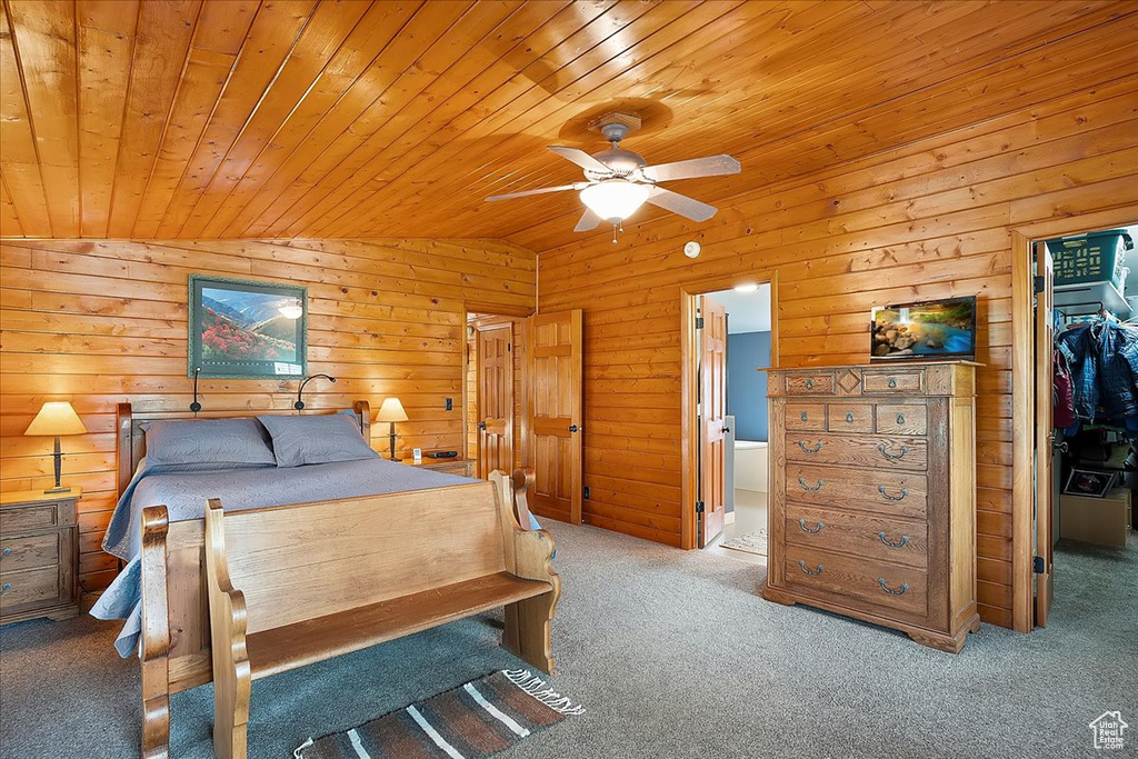 Carpeted bedroom with wooden ceiling, a spacious closet, a closet, wood walls, and vaulted ceiling