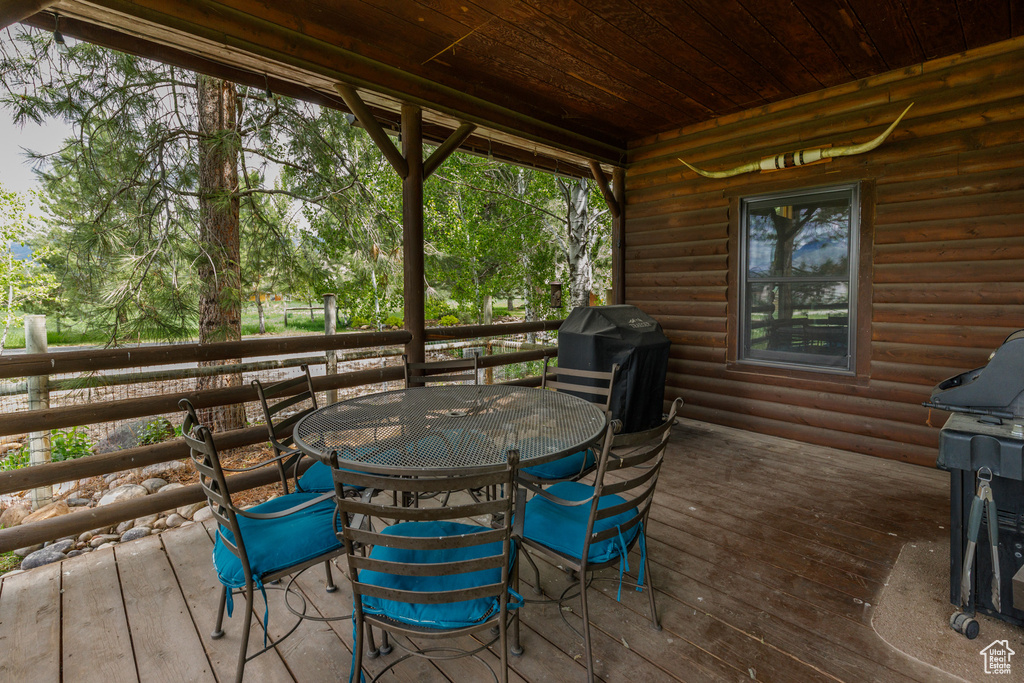 Wooden terrace featuring outdoor dining space and grilling area