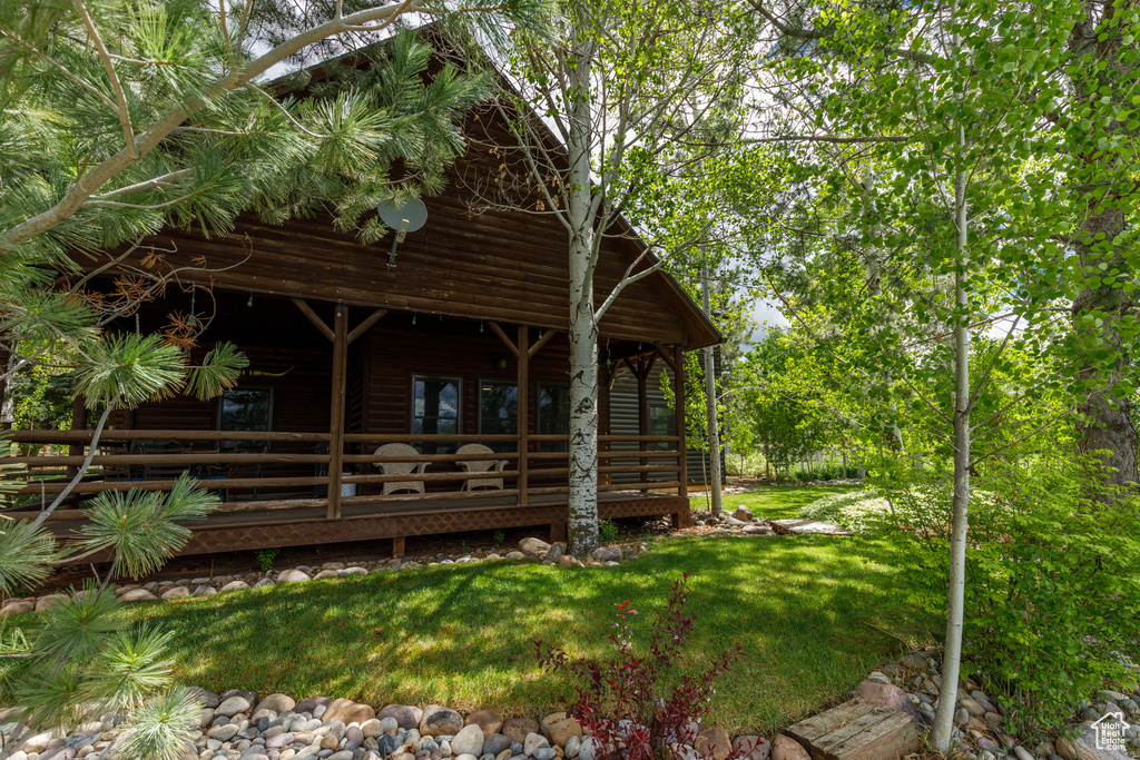 Rear view of house featuring a wooden deck, a yard, and log veneer siding