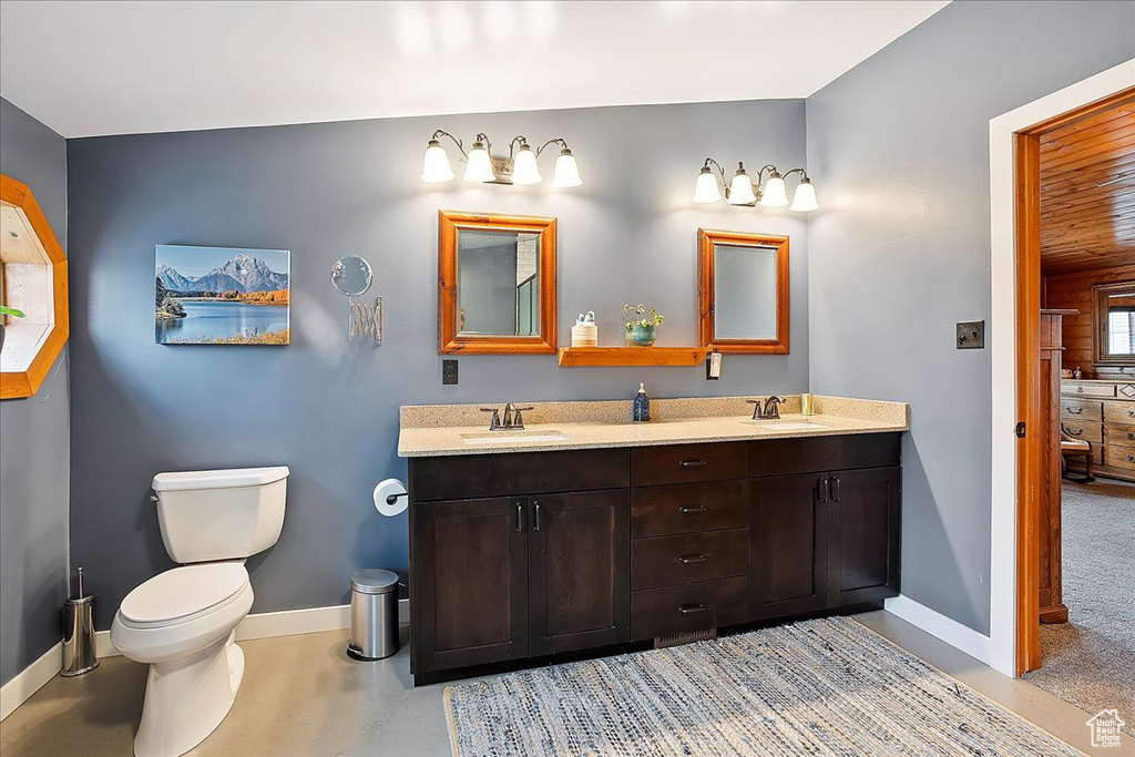 Full bathroom featuring baseboards, toilet, and double vanity