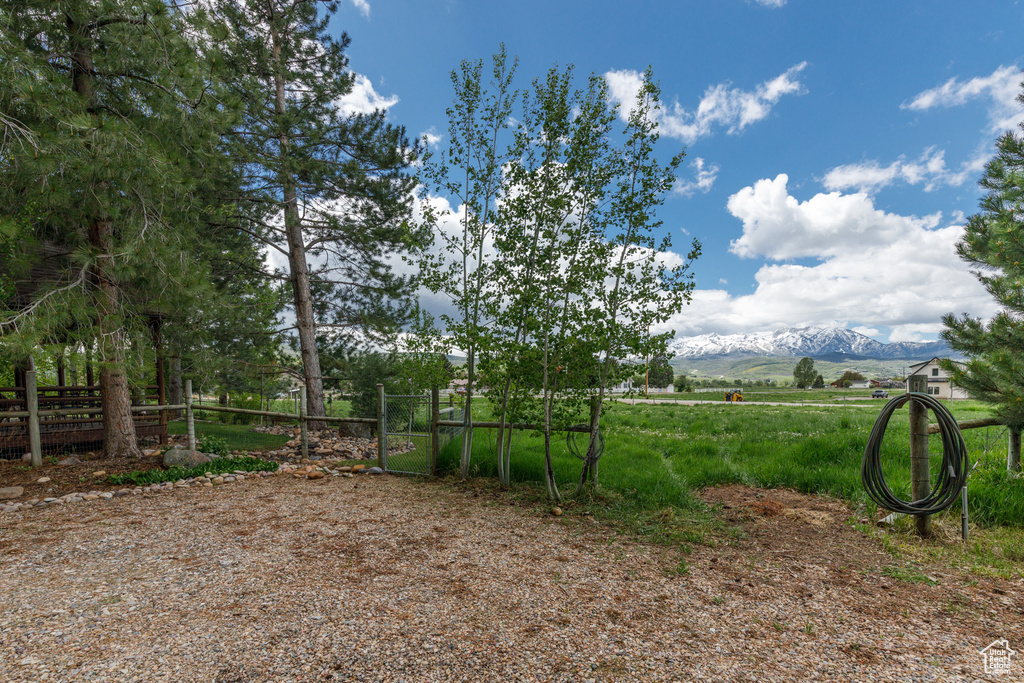 View of yard with fence, a mountain view, and a view of rural / pastoral area