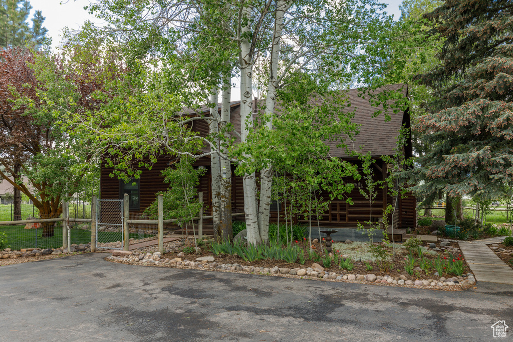 View of front of property with a shingled roof, a gate, and fence