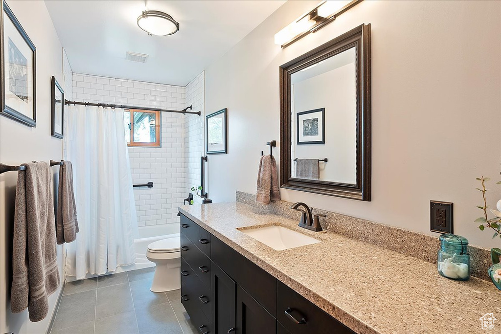 Full bathroom featuring tile patterned floors, vanity, toilet, and shower / tub combo