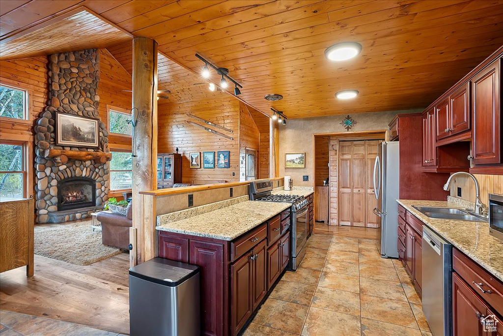 Kitchen featuring stainless steel appliances, wood ceiling, a sink, a fireplace, and open floor plan