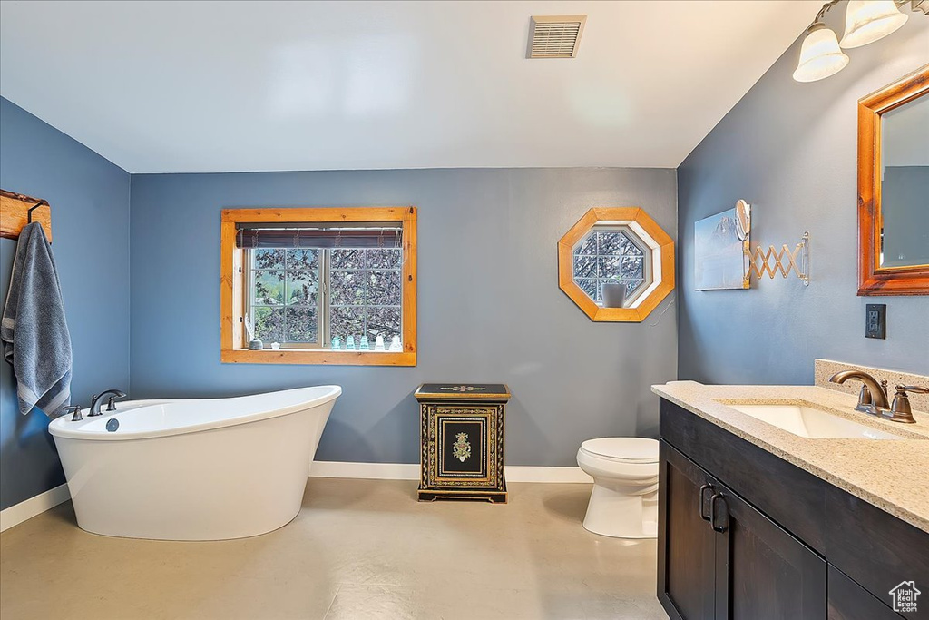 Full bathroom featuring finished concrete floors, baseboards, vanity, and a freestanding tub