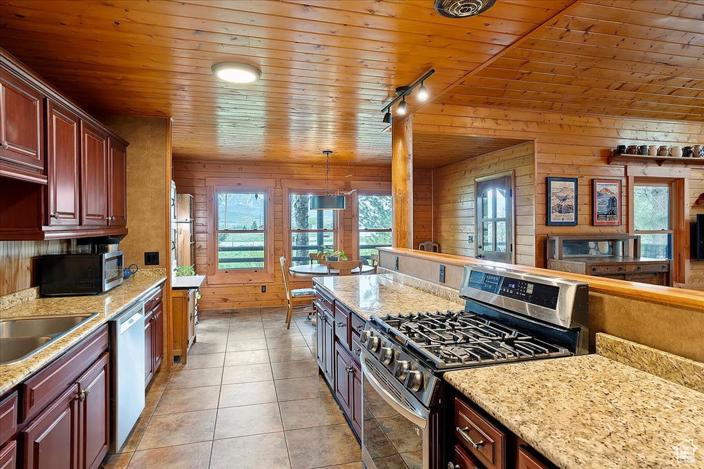 Kitchen featuring stainless steel appliances, wooden ceiling, reddish brown cabinets, light stone counters, and light tile patterned flooring