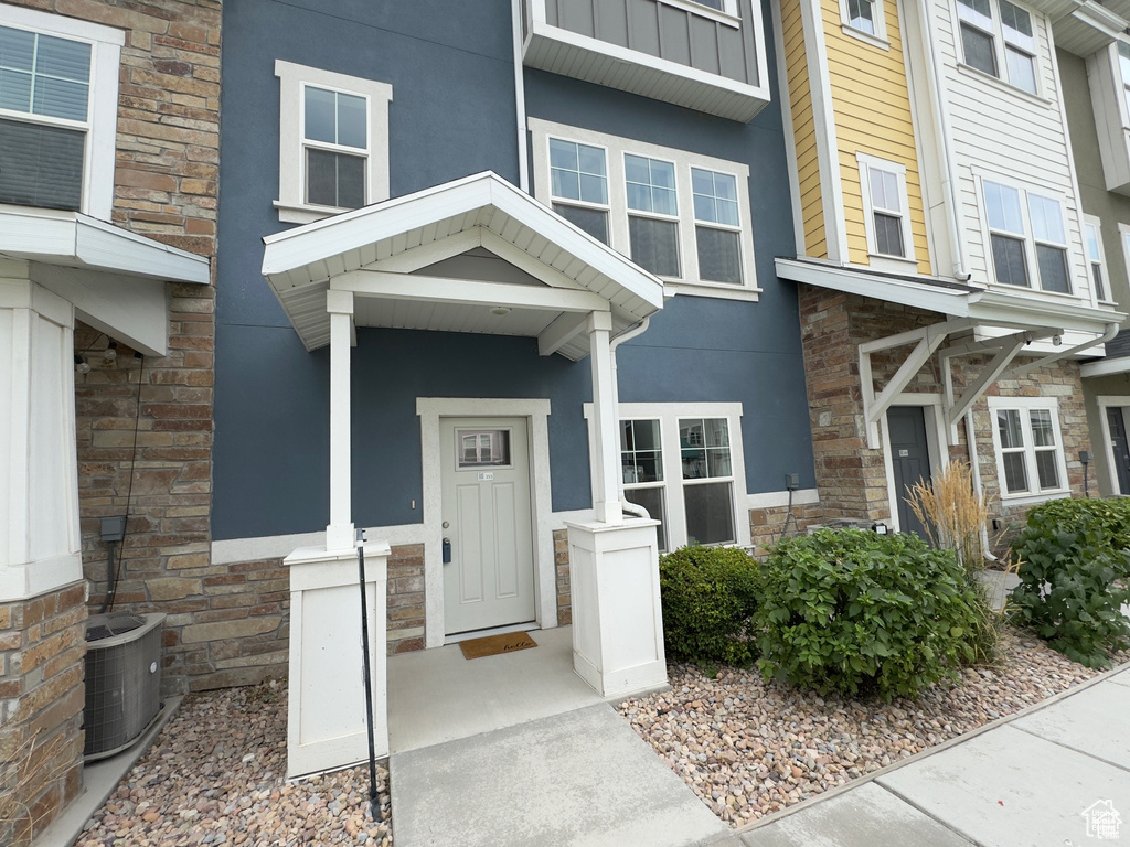 Entrance to property with central AC, stone siding, and stucco siding