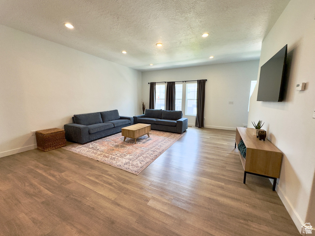 Living area with a textured ceiling, wood finished floors, recessed lighting, and baseboards