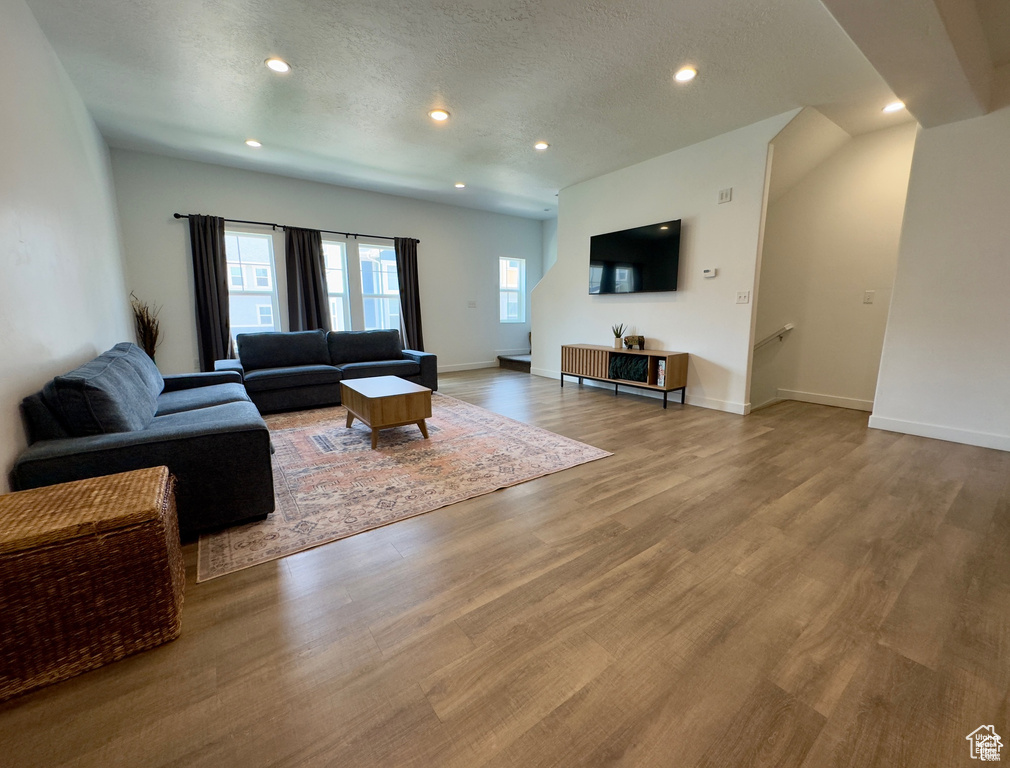 Living room featuring wood finished floors, recessed lighting, baseboards, and a textured ceiling