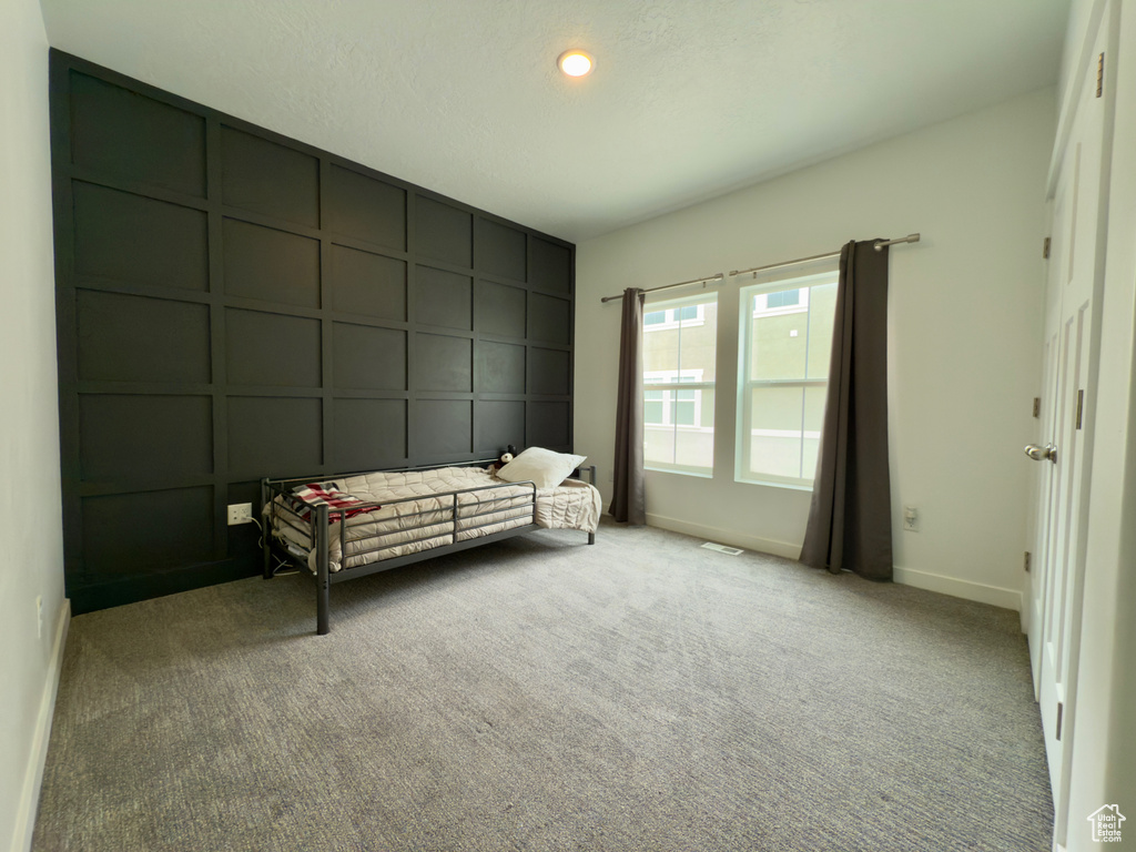 Bedroom with a decorative wall, baseboards, and carpet