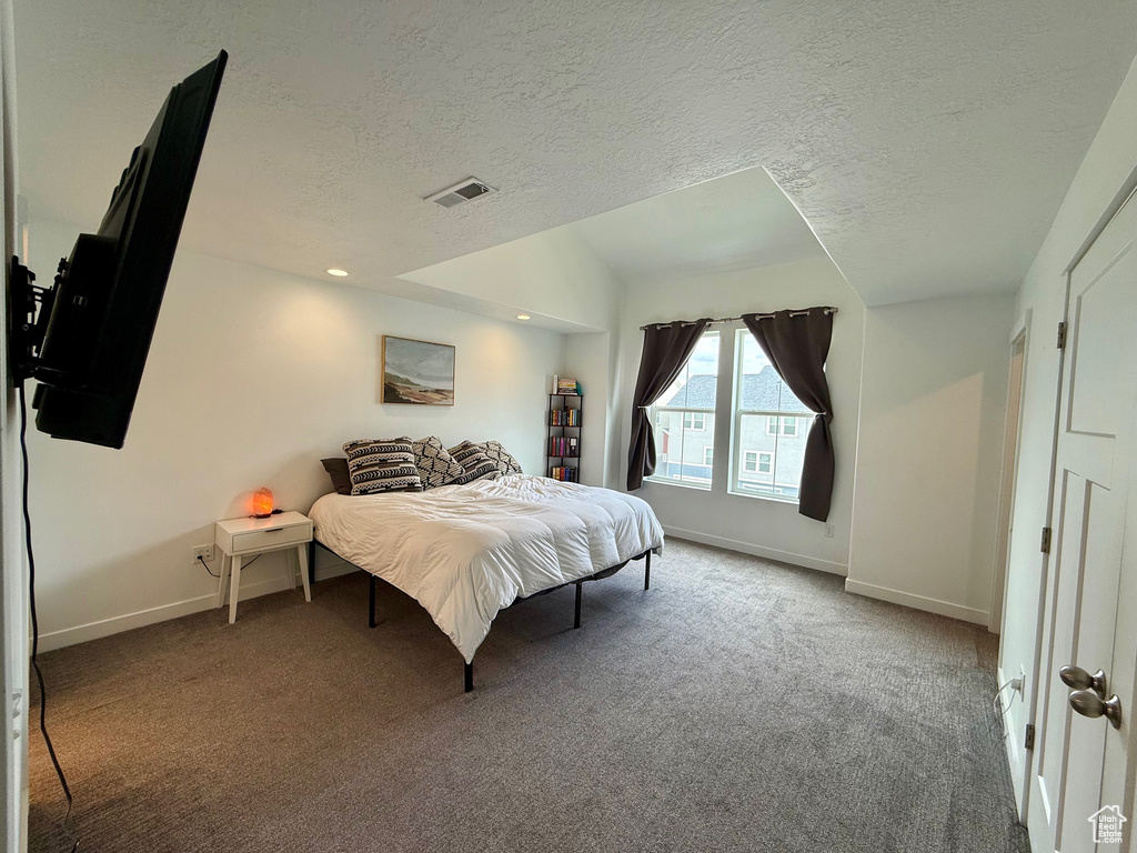 Bedroom with carpet, baseboards, and a textured ceiling