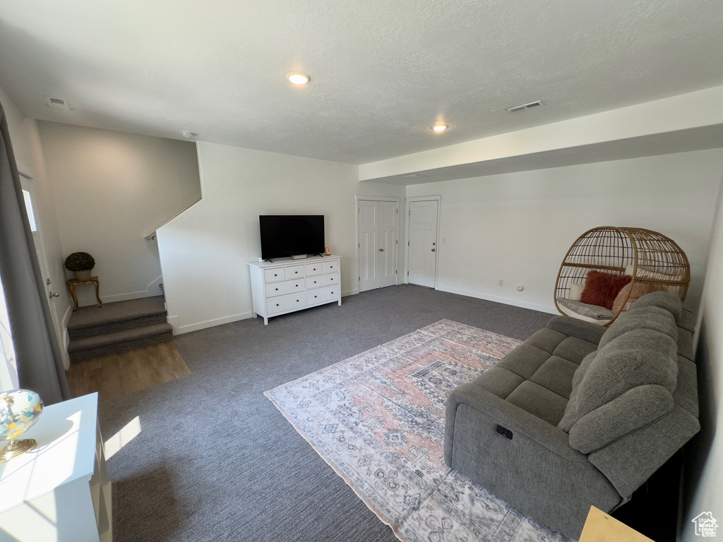 Carpeted living room with stairs, baseboards, and recessed lighting